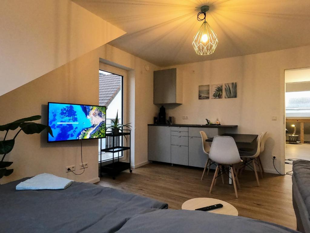 a room with a bed and a kitchen with a tv at Neubau 2-Zimmerwohnung in Hochdorf in Hochdorf