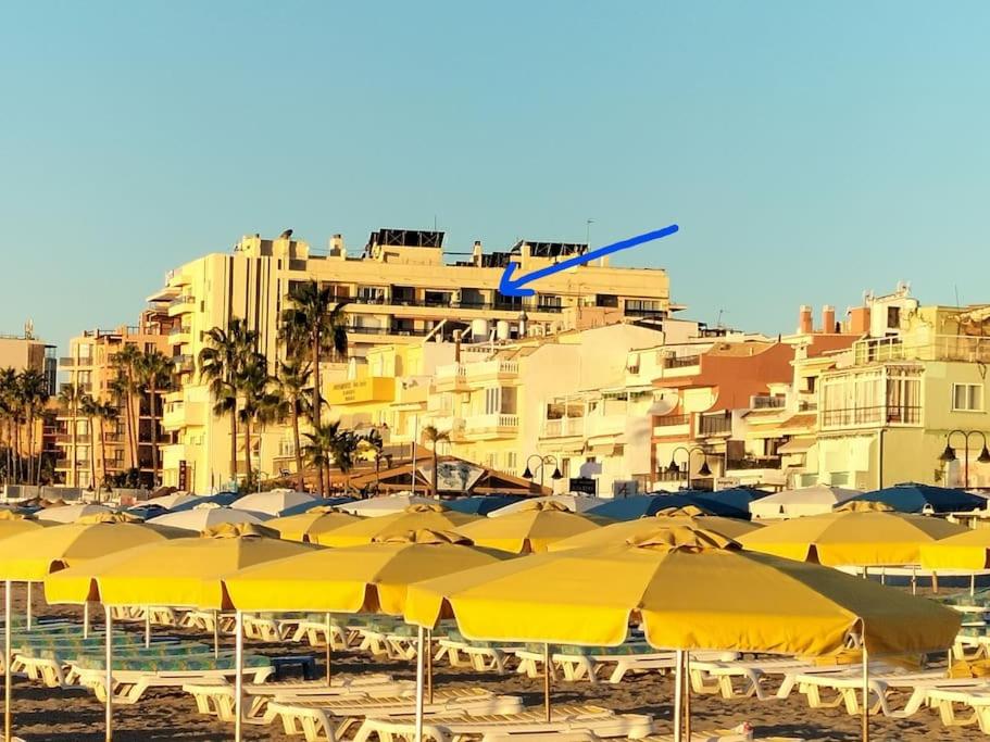 a bunch of yellow umbrellas on a beach with buildings at APARTAMENTO 1ª LINEA PLAYA GARAJE PISCINAS TERRAZA in Torremolinos