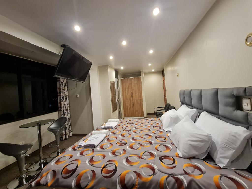 a bedroom with a large bed and a flat screen tv at Hostal Tuki Huancayo in Huancayo