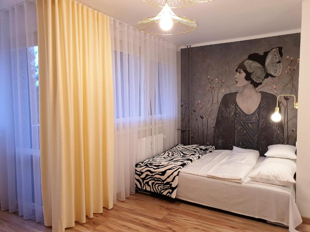 a bedroom with a bed with a painting of a woman at Apartamencik przy starówce in Lądek-Zdrój
