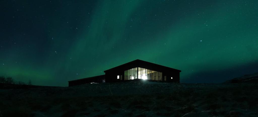 a building with a window in a field at night at Basalt Hotel in Borgarnes