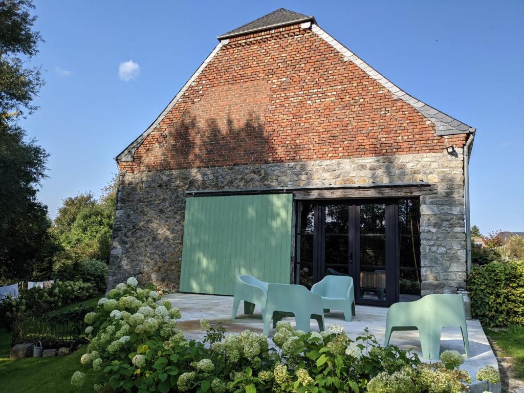 a brick building with two chairs and a green screen at La Grange de Dourlers in Dourlers