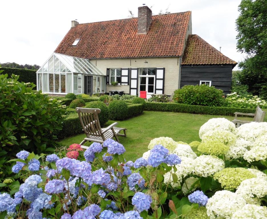 una casa con un jardín con flores azules y blancas en hoeve onder de eik en Jabbeke