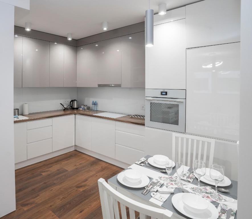 a kitchen with white cabinets and a table with chairs at Apartament AQUAROOM Reda in Reda