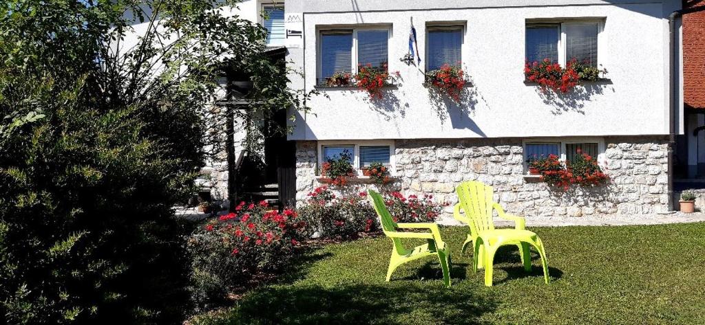Križe的住宿－Apartmaji Mojca，两把黄色椅子坐在房子前面的院子中