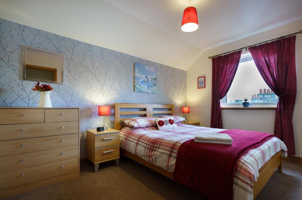 a bedroom with a bed and a dresser and a window at Lossiemouth Haven in Lossiemouth