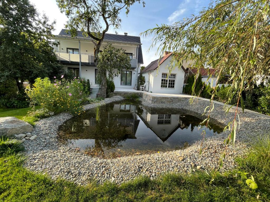 uma casa com um lago em frente a uma casa em Ferienwohnung im Westallgäu em Bad Wurzach