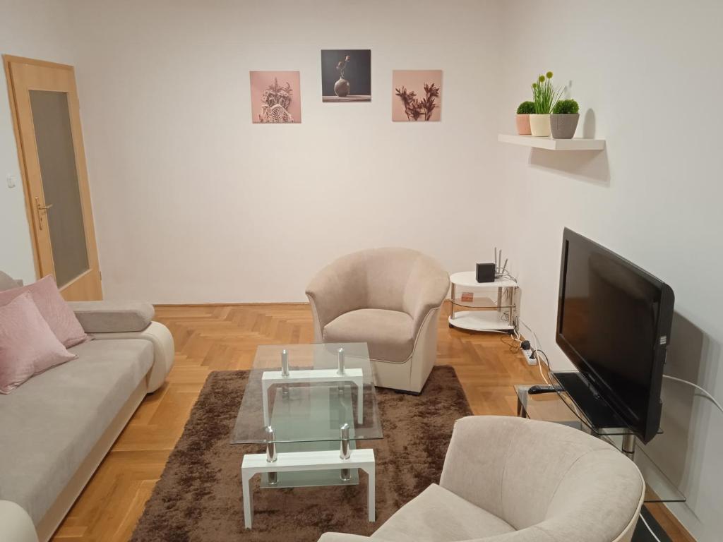 a living room with a couch and two chairs and a tv at Family apartment-családias hangulat in Győr