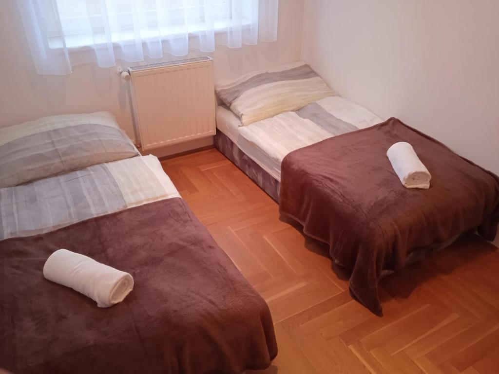 2 łóżka w pokoju z drewnianą podłogą w obiekcie Family apartment-családias hangulat w Győr