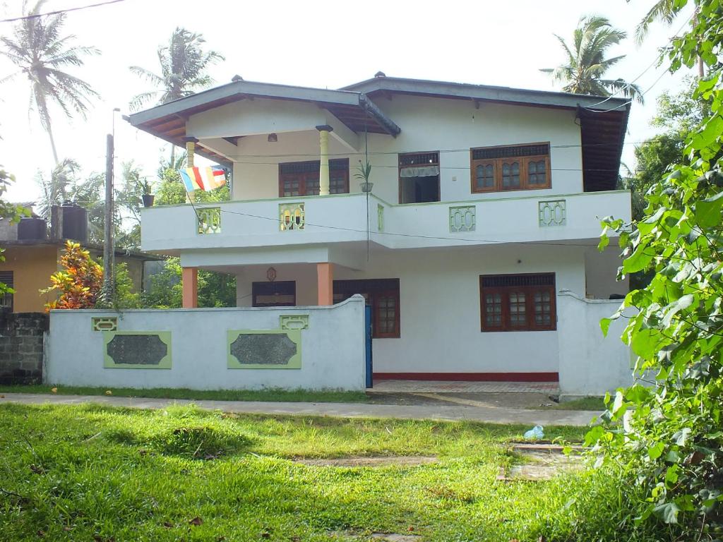 a white house with a balcony on top of it at Arogya Resort in Ambalangoda