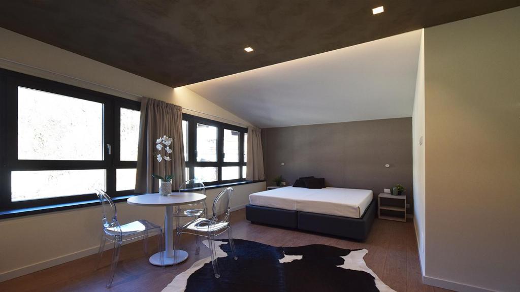 a bedroom with a bed and a table and some windows at La Meira Sermig Casa Ferie in Crissolo
