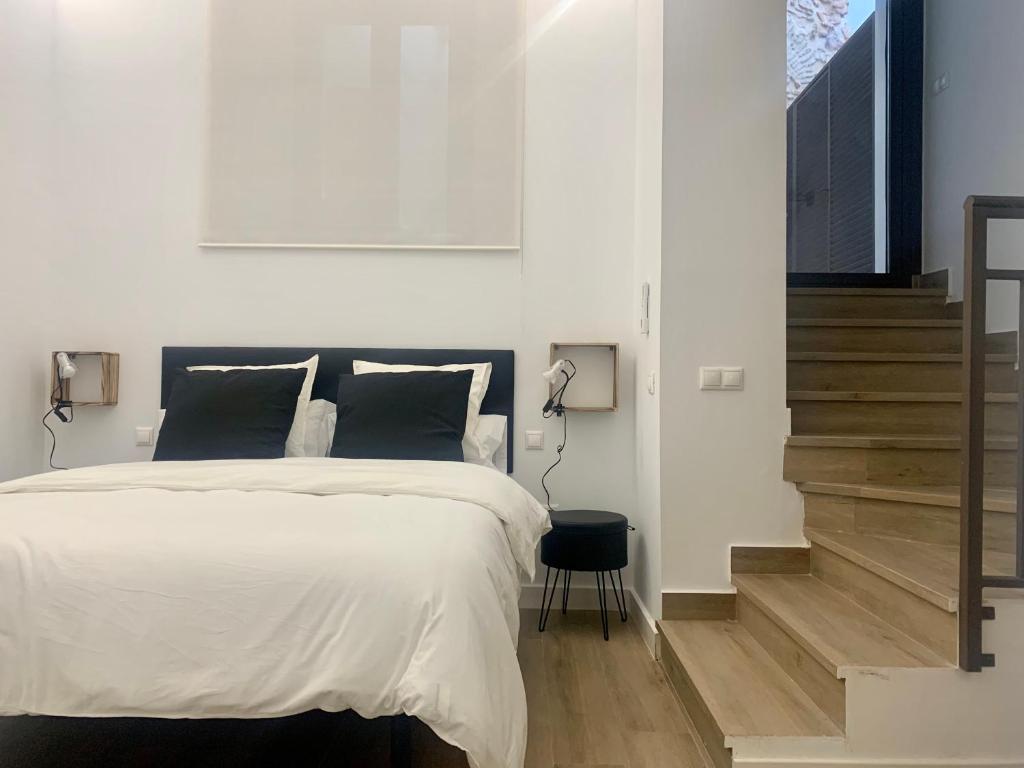 a bedroom with a large bed and a staircase at Puerta de Caceres Apartamento 1 in Cáceres