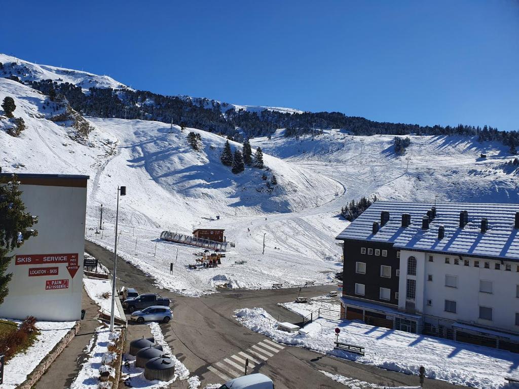 una montaña cubierta de nieve con un edificio y una pista de esquí en Résidence LES CHAMOIS Pied des pistes Chamrousse, en Chamrousse