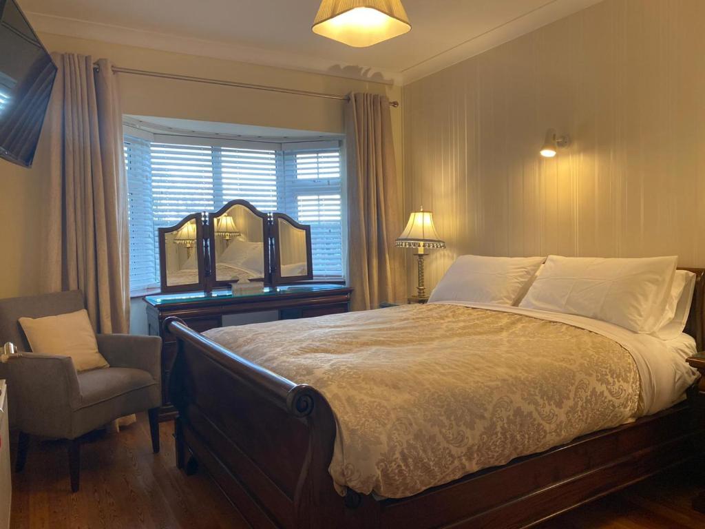 1 dormitorio con cama, silla y espejo en Woodhaven Manor h91rc9d en Galway