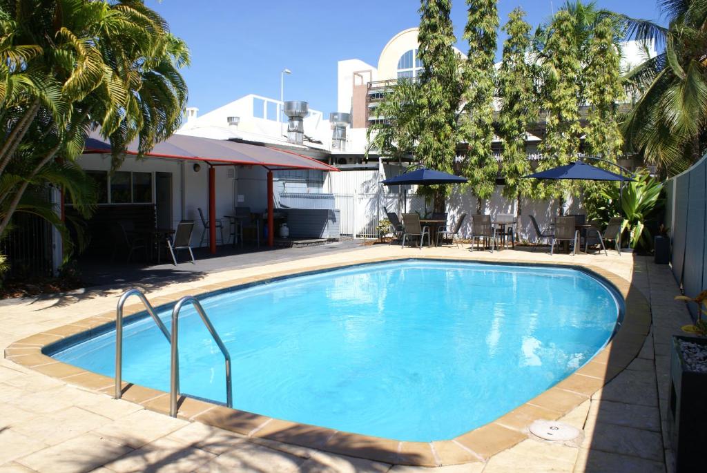 une grande piscine bleue avec des chaises et des parasols dans l'établissement Darwin Poinciana Inn, à Darwin