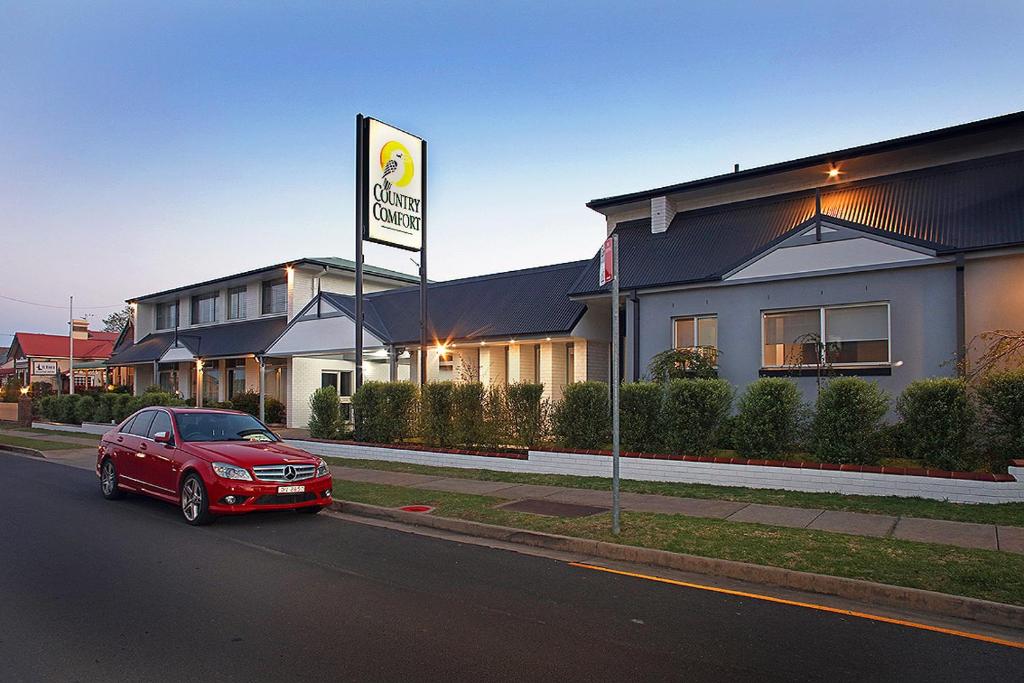 un coche rojo estacionado frente a un edificio en Country Comfort Armidale, en Armidale