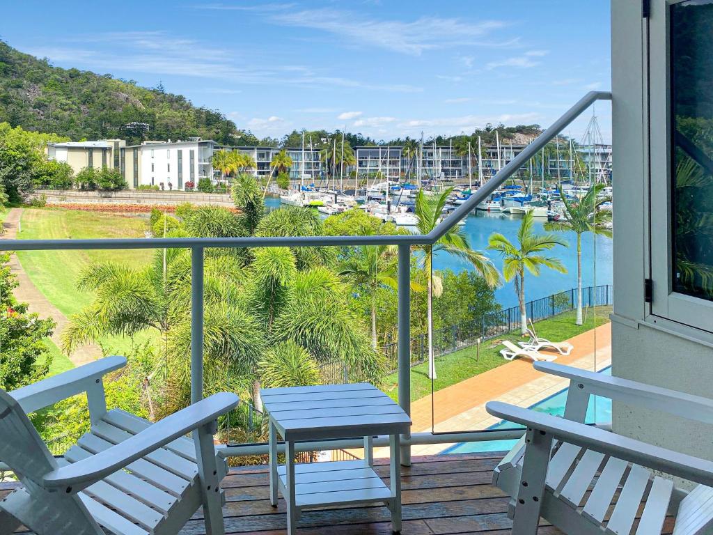 two chairs and a table on a balcony with a view of the water at Beachside Apartment 14 in Nelly Bay