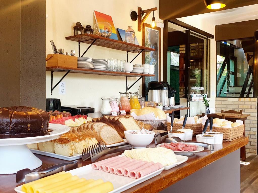 a buffet line with different types of bread and pastries at Pousada Villa Embaú in Guarda do Embaú