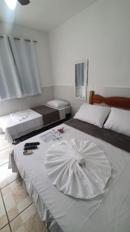 um quarto com 2 camas e uma grande colcha branca em Pousada Pérola Verde em Abraão