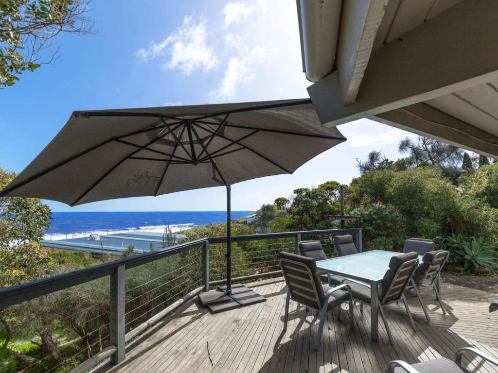 eine Terrasse mit einem Tisch, Stühlen und einem Sonnenschirm in der Unterkunft Coorumbene 8 Scenic Way in Normanville