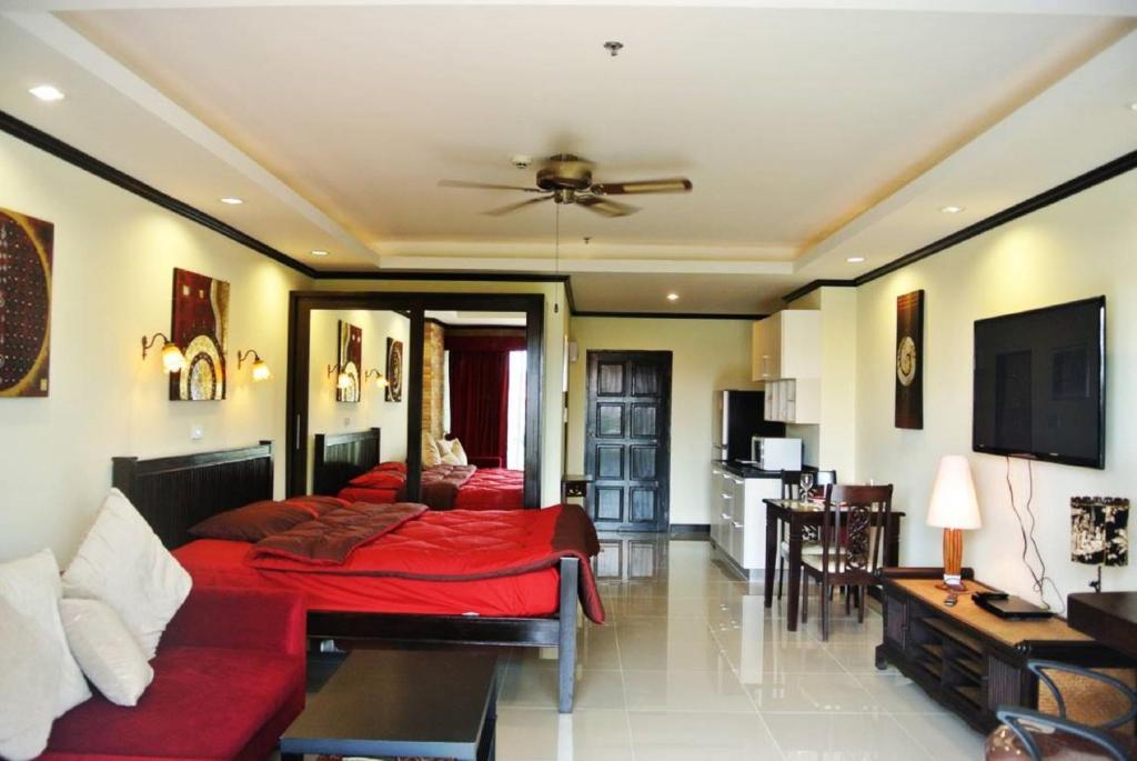 a bedroom with a red bed and a living room at View Talay 5 studio apartment - close to the beach in Pattaya South
