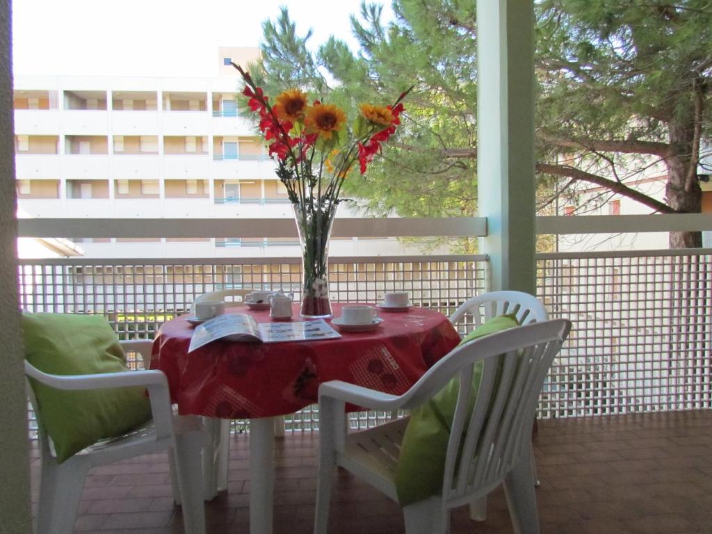 een tafel met een vaas met bloemen op een veranda bij Holiday in Bibione by the beach - Beahost in Bibione