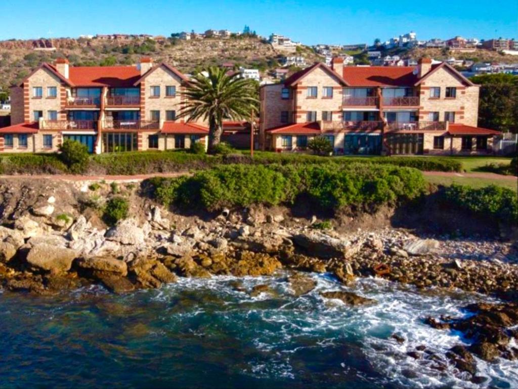 un groupe de maisons sur une falaise à côté de l'eau dans l'établissement Rosebud 4 Beacon Point, à Mossel Bay