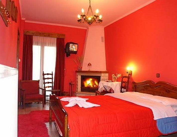 a red bedroom with a bed and a fireplace at Ουρανια Τασιου in Mikro Chorio