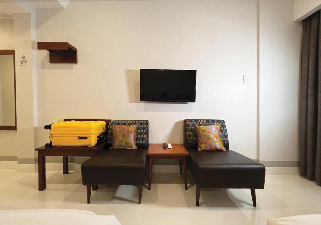 a room with two chairs and a table and a tv at Niagara Hotel in Bangkok