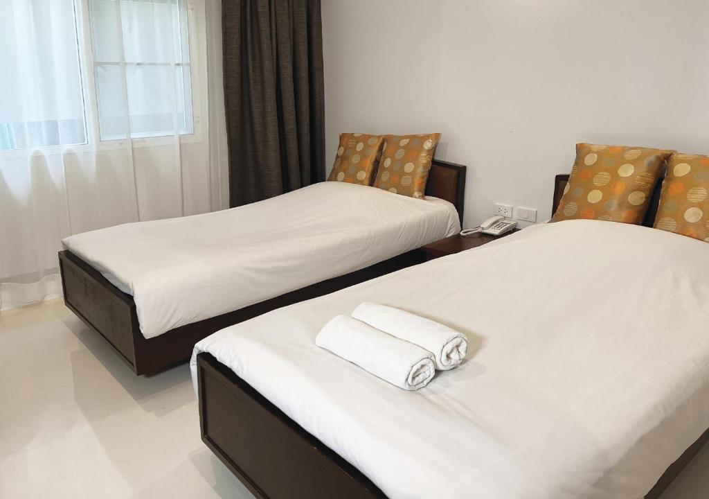 two beds in a hotel room with towels on them at Niagara Hotel in Bangkok