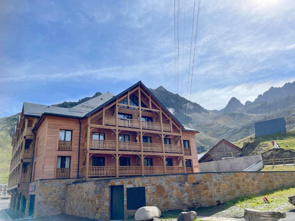 un edificio de madera con balcón en la parte superior. en L' Etoile du Pic en La Mongie