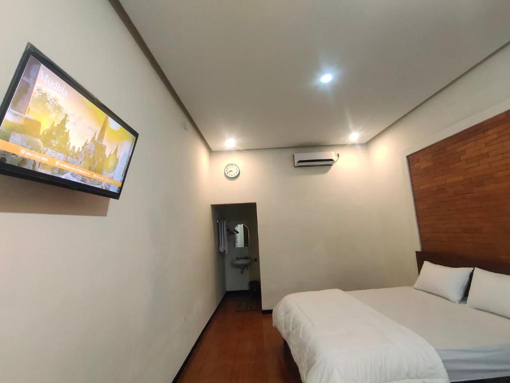 um quarto com duas camas e uma televisão na parede em Mudhia Homestay em Magelang