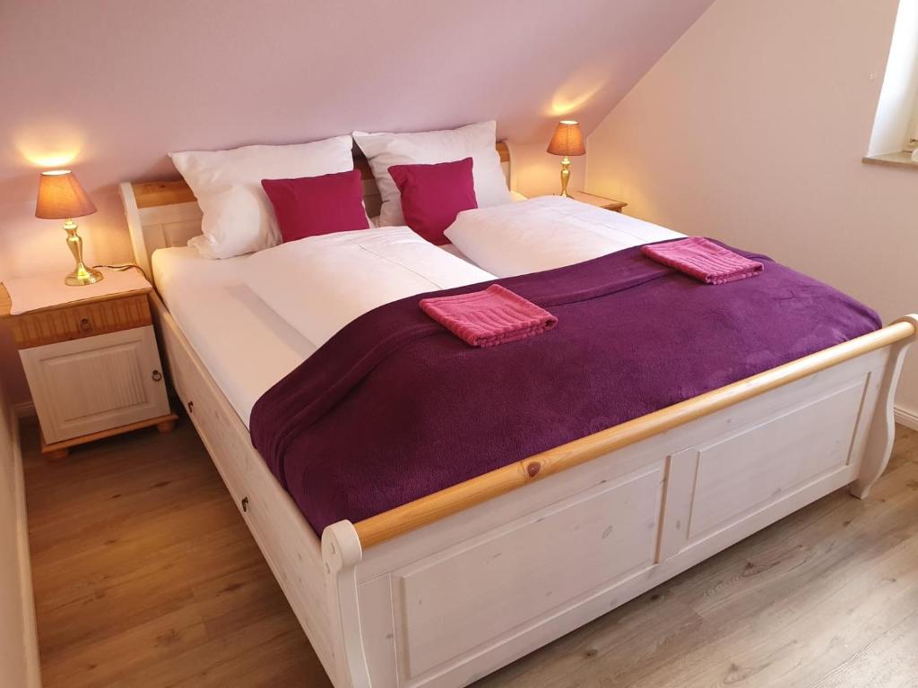 ウンデローにあるHaus Petersenの紫色のシーツと枕が備わる白い大型ベッド