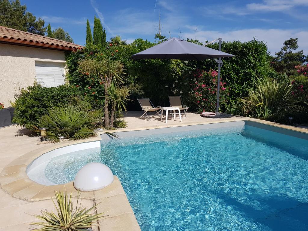 uma piscina com um guarda-sol ao lado de uma casa em Studio Villa Les Canas em Saint-Gély-du-Fesc