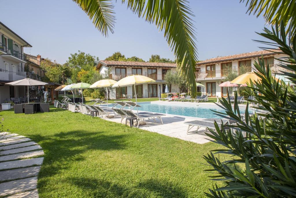 a resort pool with chairs and umbrellas at Residence Molino - Holiday Apartments in Manerba del Garda