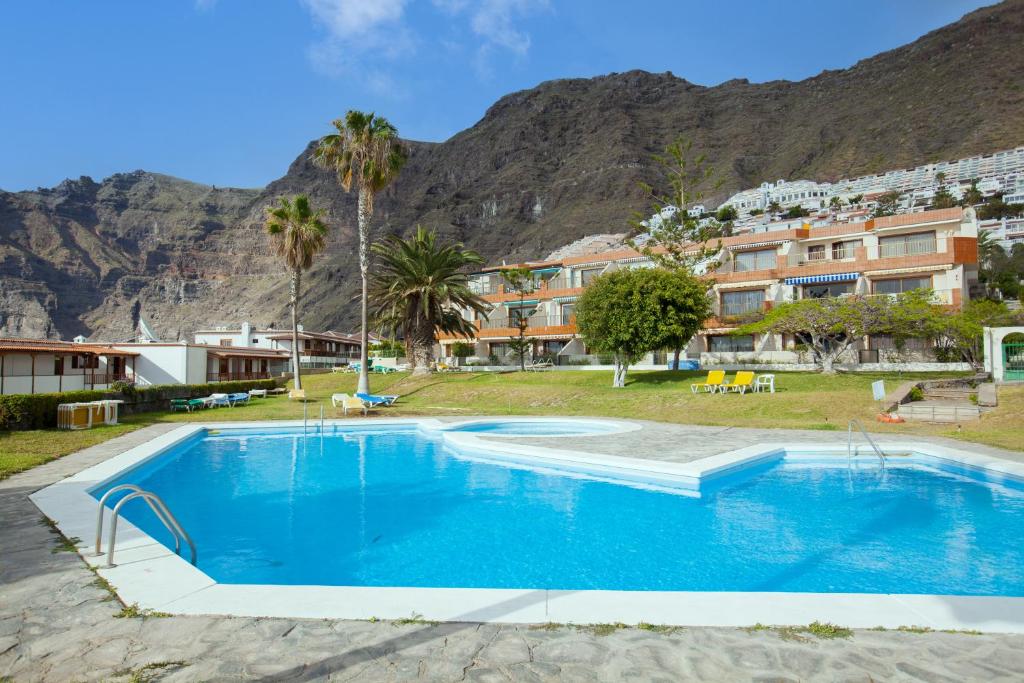 a large blue swimming pool in front of a mountain at Gigantes Cliff Holiday Home by Sydney Playa Sur in Acantilado de los Gigantes