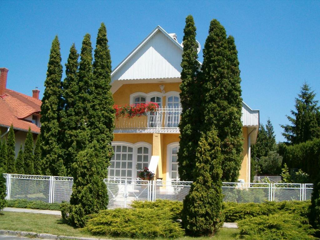żółty dom z drzewami przed nim w obiekcie Familia nyaraló 26 w mieście Balatonmáriafürdő
