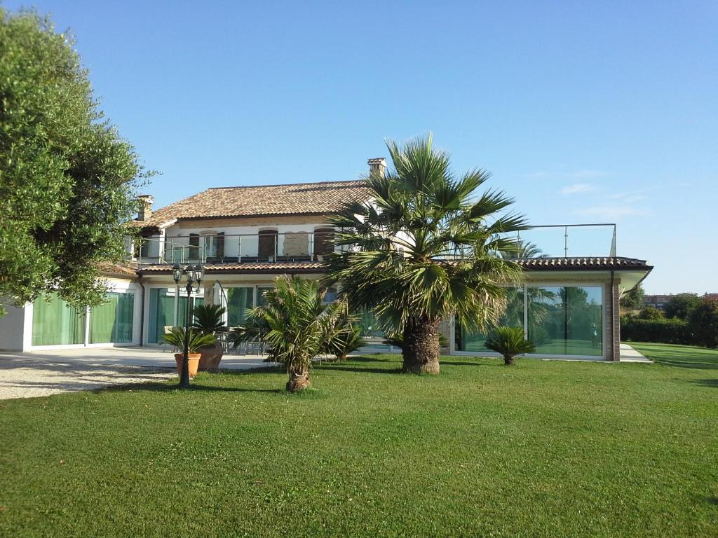 a house with a palm tree in front of it at Villa Belvedere Degli Ulivi in Osimo