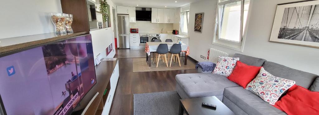 a living room with a gray couch and a kitchen at A 50 metros del Paseo Marítimo in A Coruña