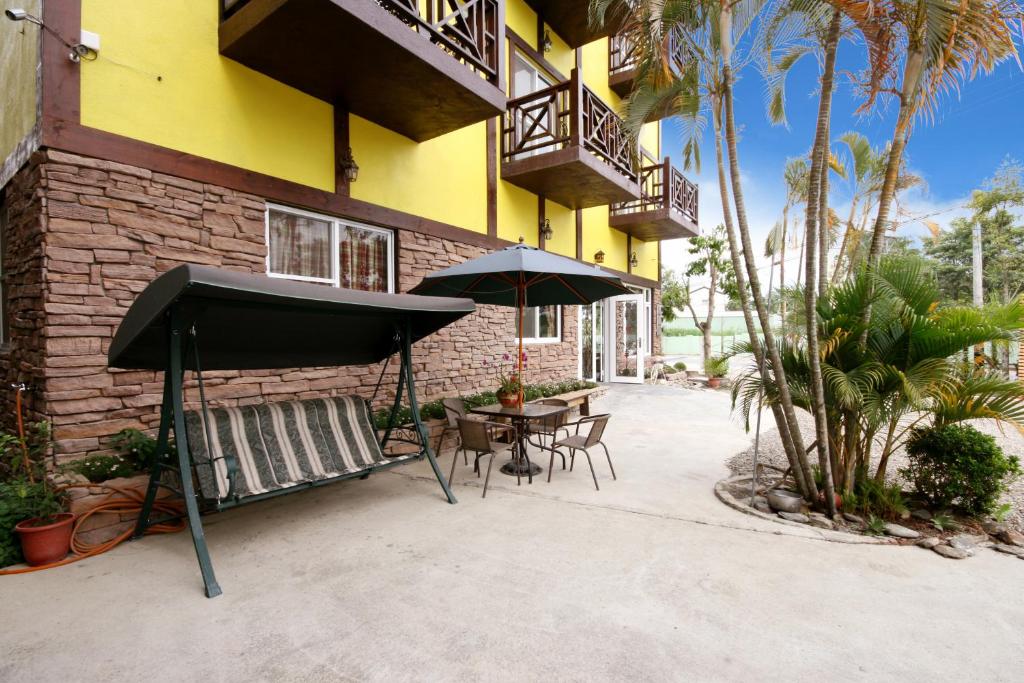 a patio with a table and an umbrella in front of a building at Pulicity Villa B&amp;B in Puli
