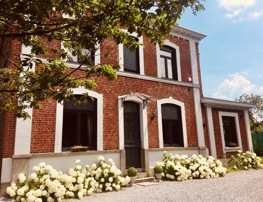 une maison en briques avec des fleurs blanches devant elle dans l'établissement La Villa des Roses - Suite & Spa, à Lys-lès-Lannoy