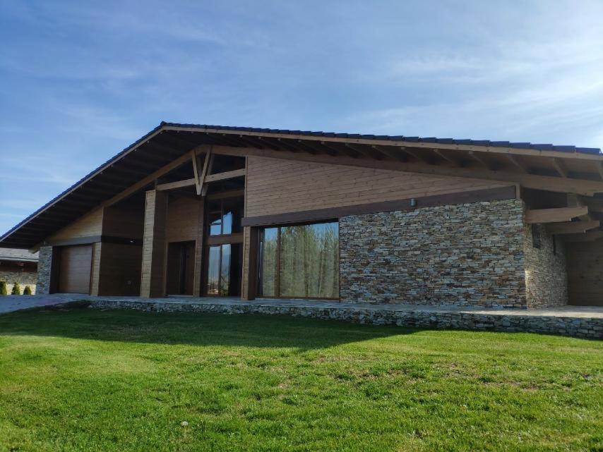 Una casa con un patio con césped en frente. en Villa Naya, Pirin Golf & Spa, en Bansko