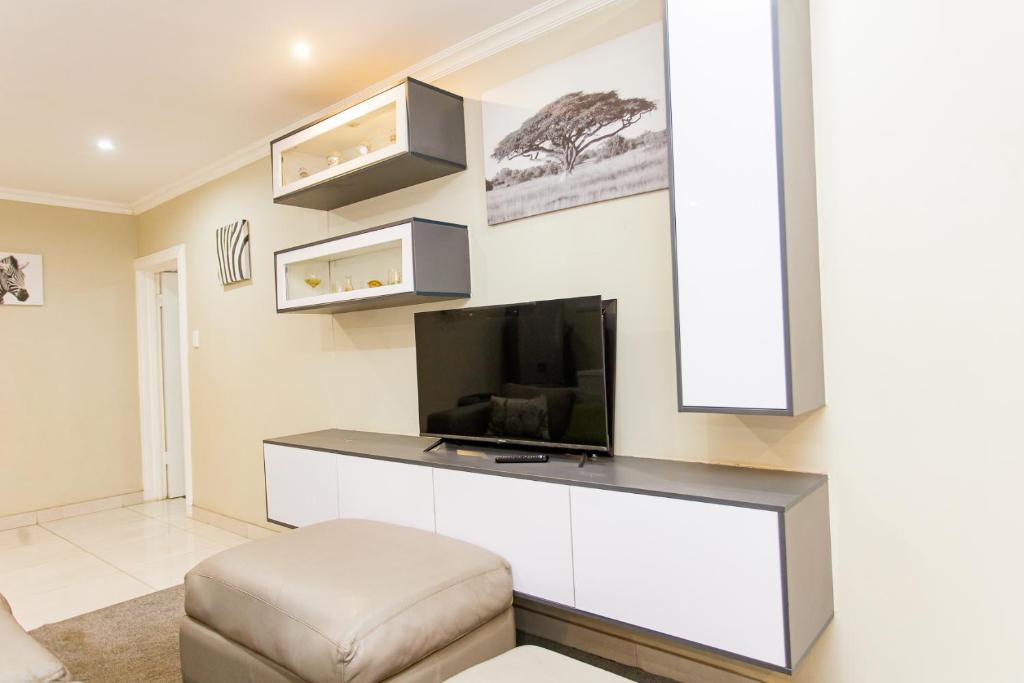 a living room with a flat screen tv and a couch at The Hide on kilburn in Roodepoort