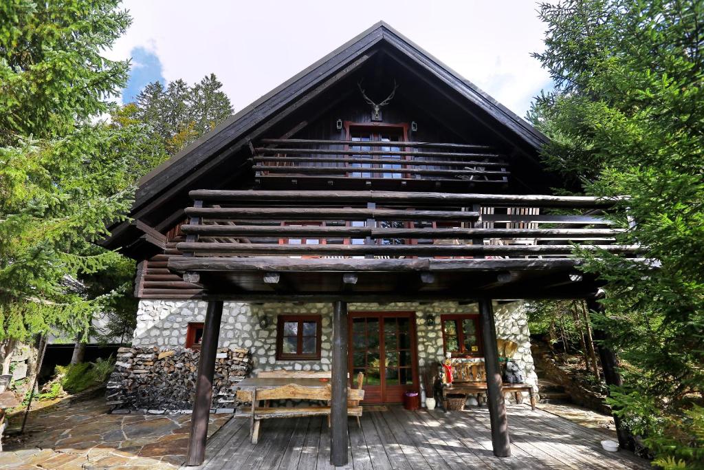 a log cabin in the woods with a large balcony at Mountain Dreams House - Stunning view over Lake Jasna! in Kranjska Gora