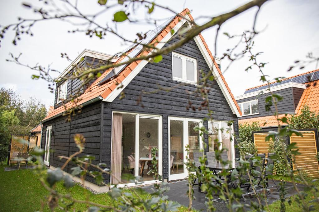 uma casa com revestimento preto e um pátio em Het Mienterbos em De Koog