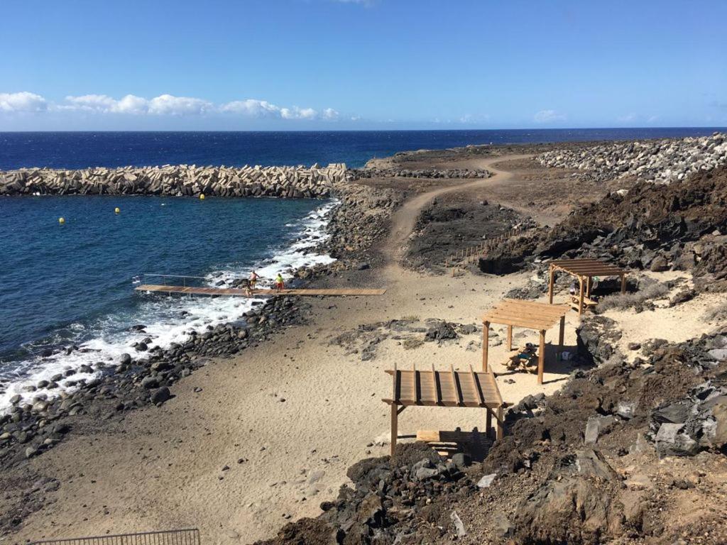 a beach with two benches and the ocean at Apto Tagoro, La Restinga in La Restinga