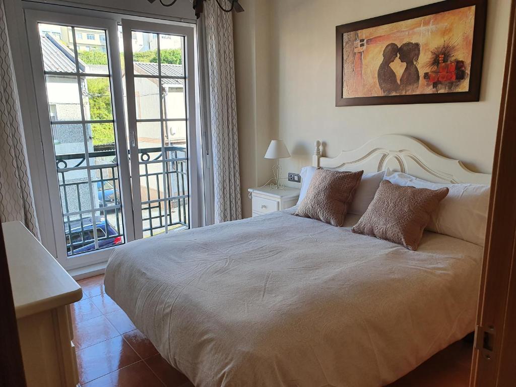 um quarto com uma cama grande e uma janela grande em Apartamentos Nordés2 em Malpica de Bergantiños
