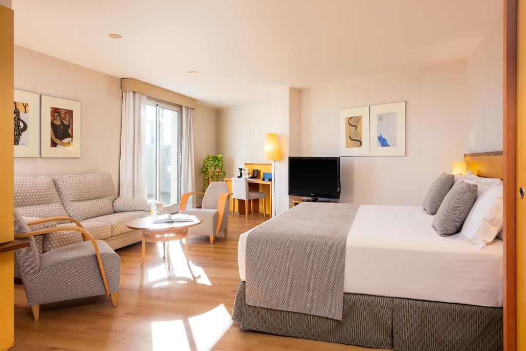 Habitación de hotel con cama y sala de estar. en Hotel Castellon Center Affiliated by Meliá, en Castellón de la Plana