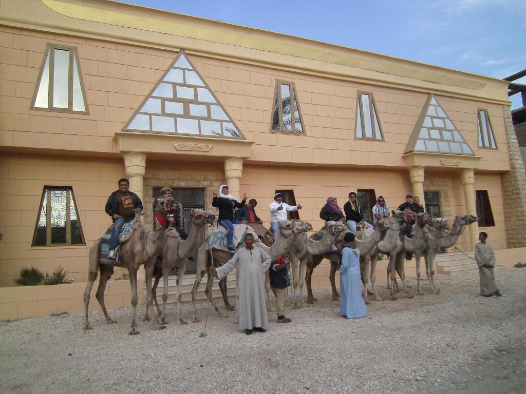un grupo de personas en camellos frente a un edificio en Pyramids Luxor Hotel & SPA, en Luxor
