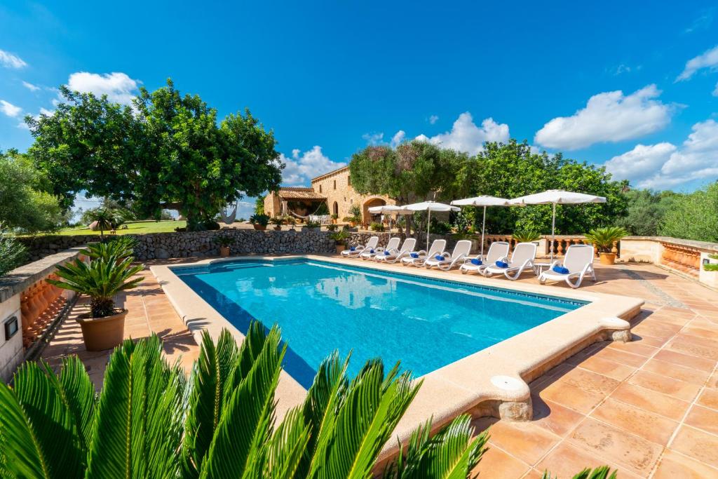 a pool with chairs and umbrellas in a backyard at Son Poca Palla in Sant Llorenç des Cardassar